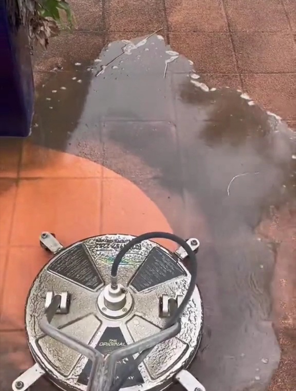 A rotary surface cleaner working across tiled paving